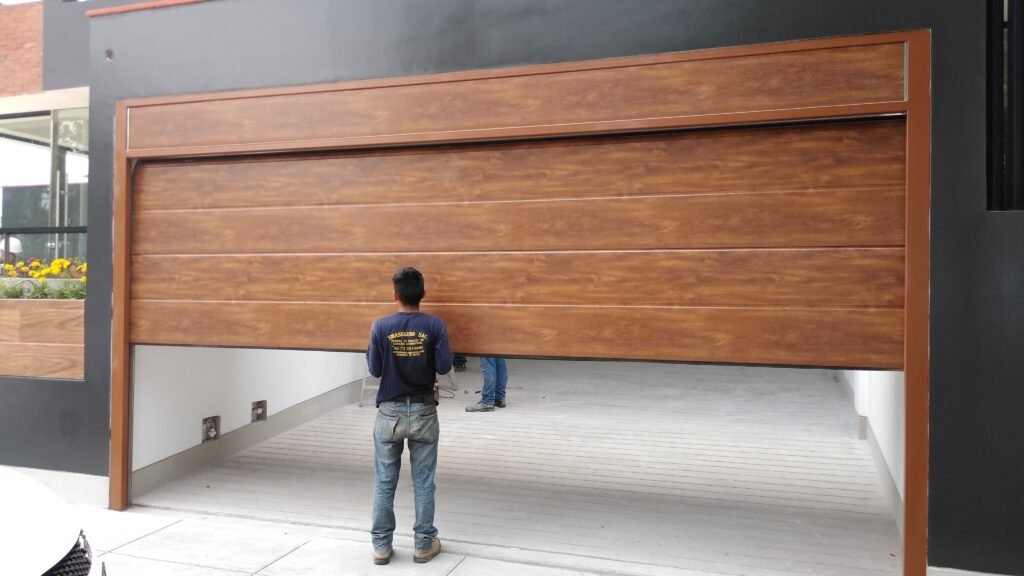 “Instalación de puerta seccional color cedro en Lima – panel importado y sistema automatizado SMASEGURO.”